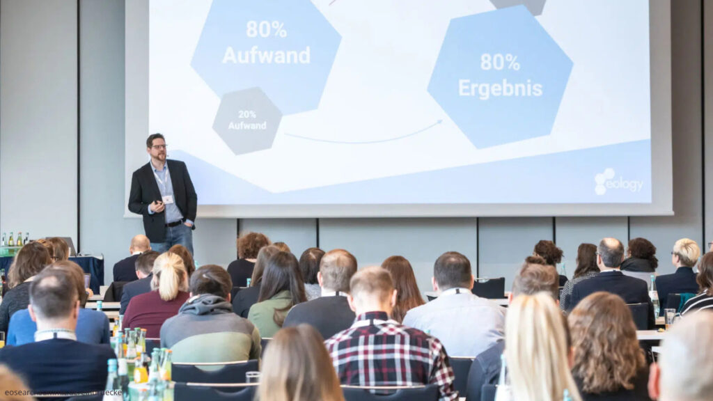 Publikum vor der eoSearchSummit-Bühne mit Vortragsredner