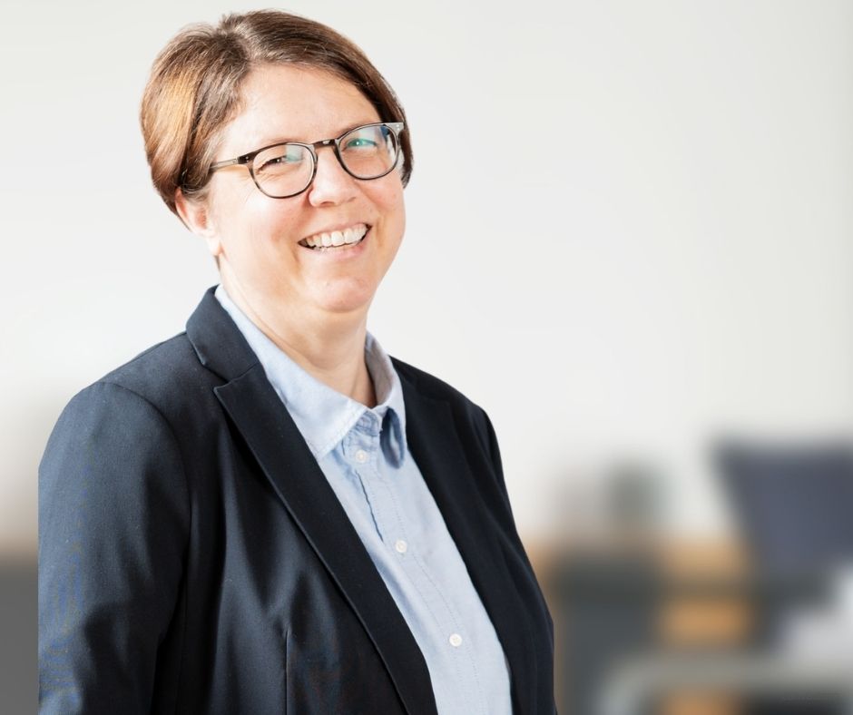 Büro-Assistenz: Bettina stehend vor Ihrem Arbeitsplatz