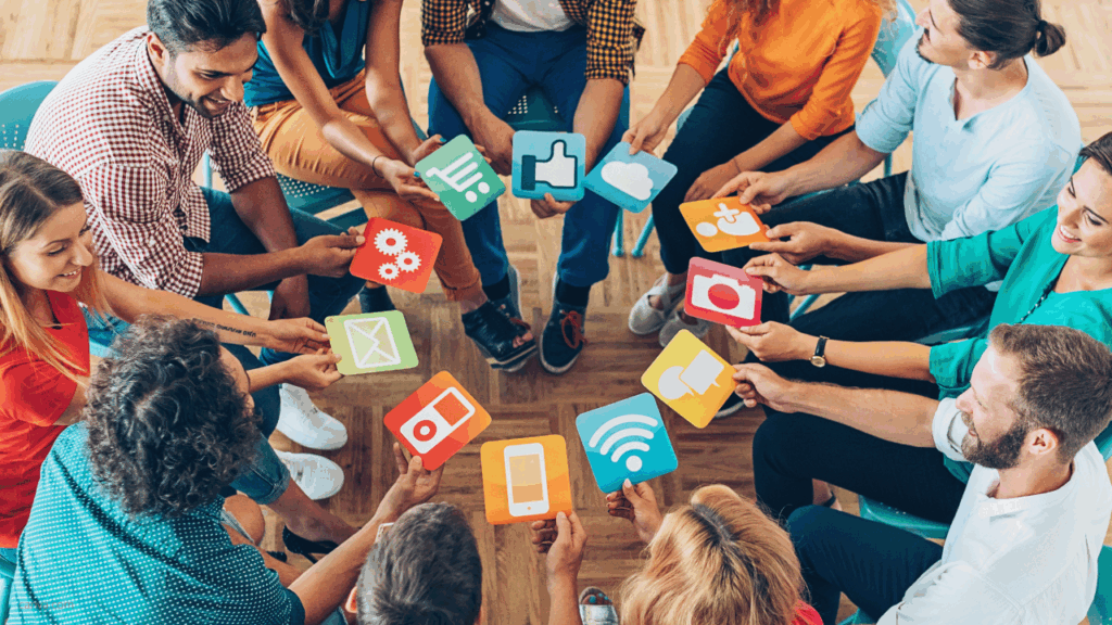 Gruppe von Personen im Stuhlkreis die Social-Media-Icons aus Pappe in Händen halten