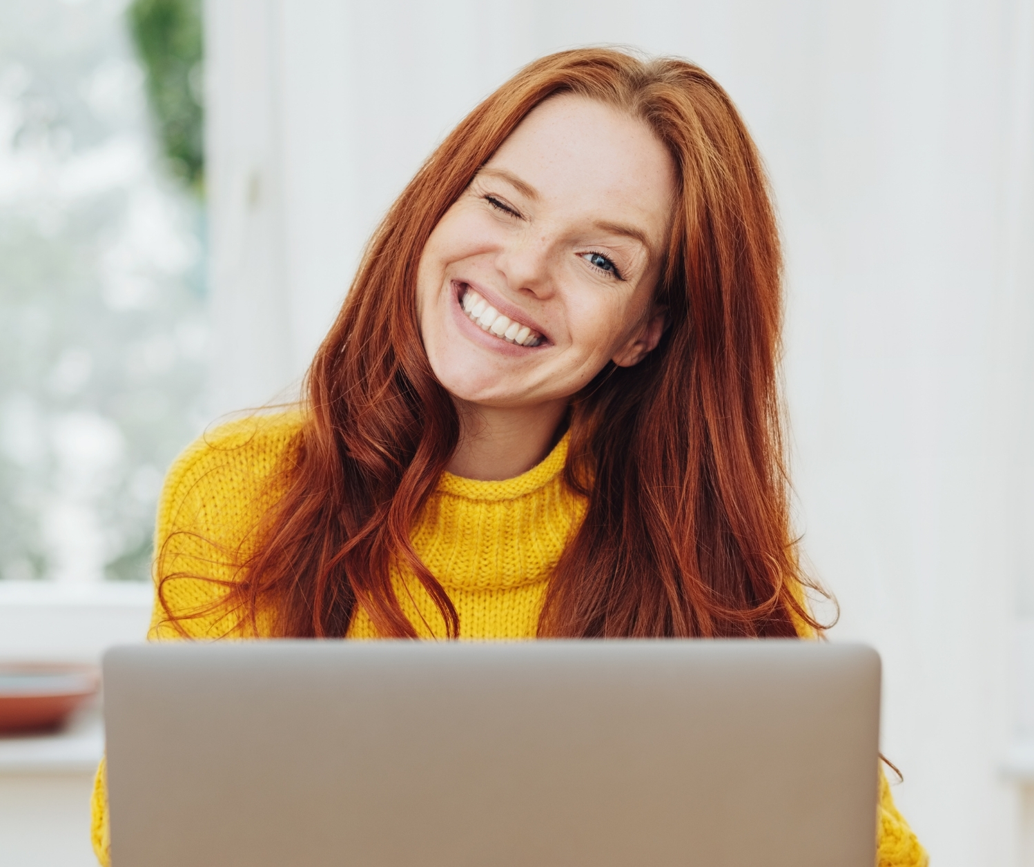 Lächelnde Social-Media-Managerin bei der Arbeit am Laptop