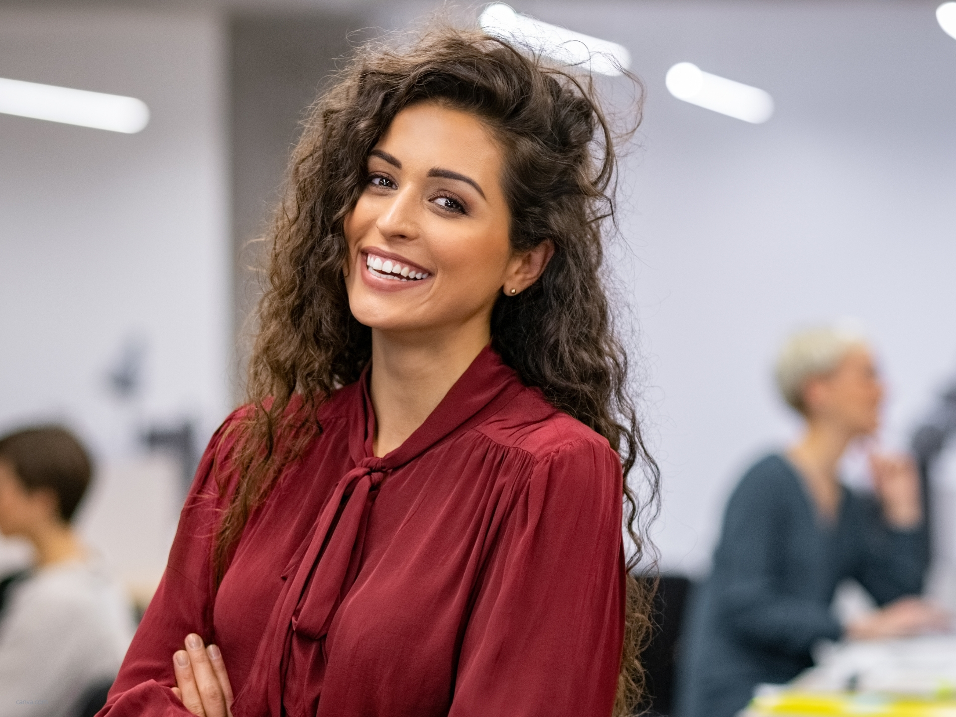 Frau aus dem Marketing steht selbstbewusst und lächelnd im Büro
