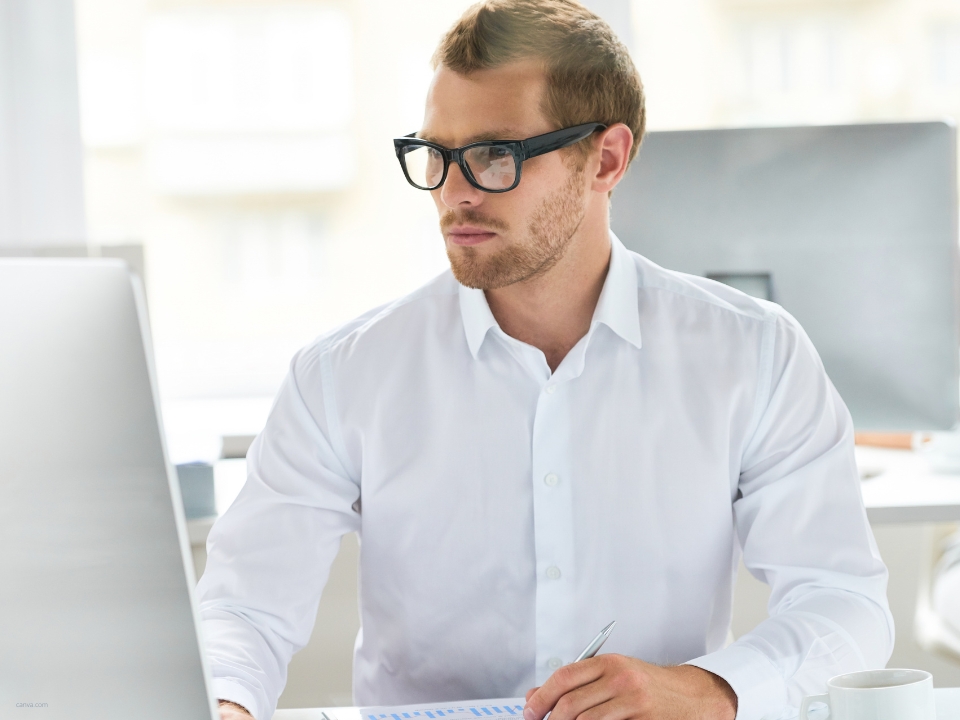 Mann arbeitet verantwortungsvoll am Computer an seinem Arbeitsplatz